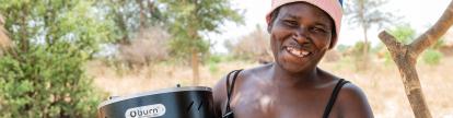 zambian woman holding improved cookstove