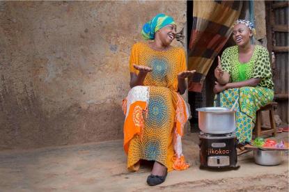 two women in africa sitting at cookstove and laughing