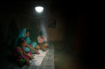 woman and two children sitting under solar lamp